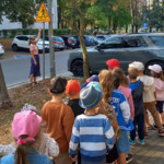Pani pokazuje dzieciom znak drogowy