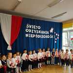 dzieci trzymają biało-czerwone kwiaty