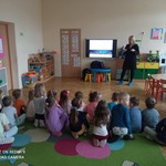 dzieci siedzą na dywanie i oglądają film edukacyjny