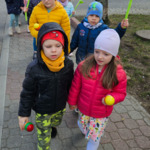 dzieci idą z grzechotkami i kwiatami