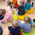 dzieci siedzą na kolorowych poduszkach