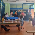 uczestnicy konkursu siedzą przy stolikach