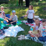 dzieci siedzą na kocu i jedzą lody