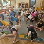 dzieci stoją na jednej nodze i dotykają ręką do podłogi