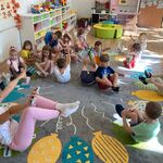 dzieci siedzą na dywanie i podnoszą ręce i nogi