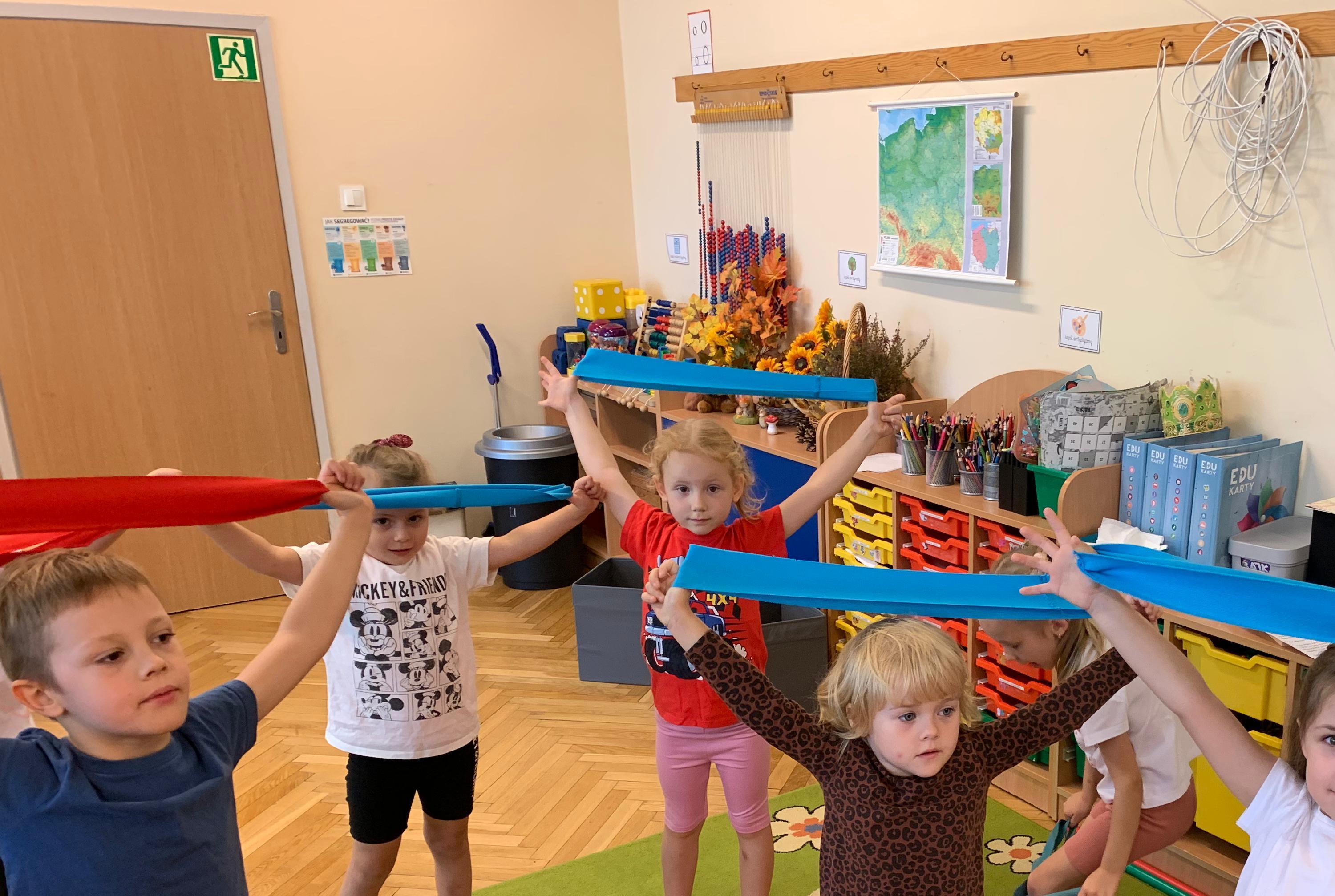 dzieci trzymają szarfy w górze