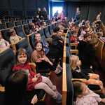 dzieci siedzą na widowni w teatrze