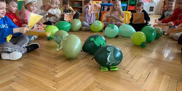zielone balony z dinozaurami przy dzieciach