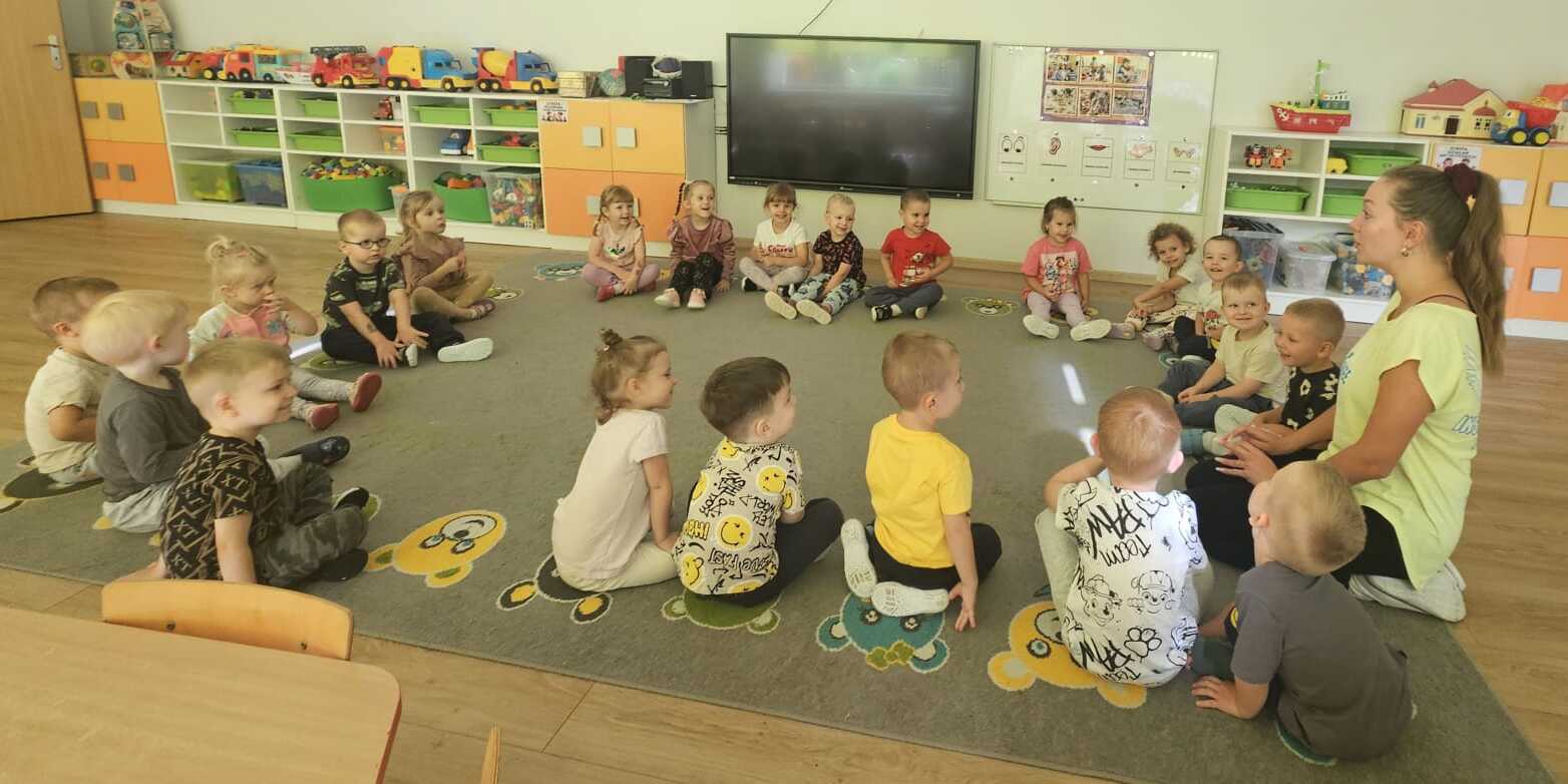 dzieci siedzą z panią na dywanie