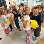 dzieci trzumają balony brzuchami